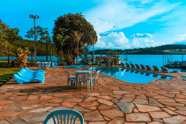 Área de piscinas com mesas e espreguiçadeiras de frente para o Lago de Furnas em Capitólio