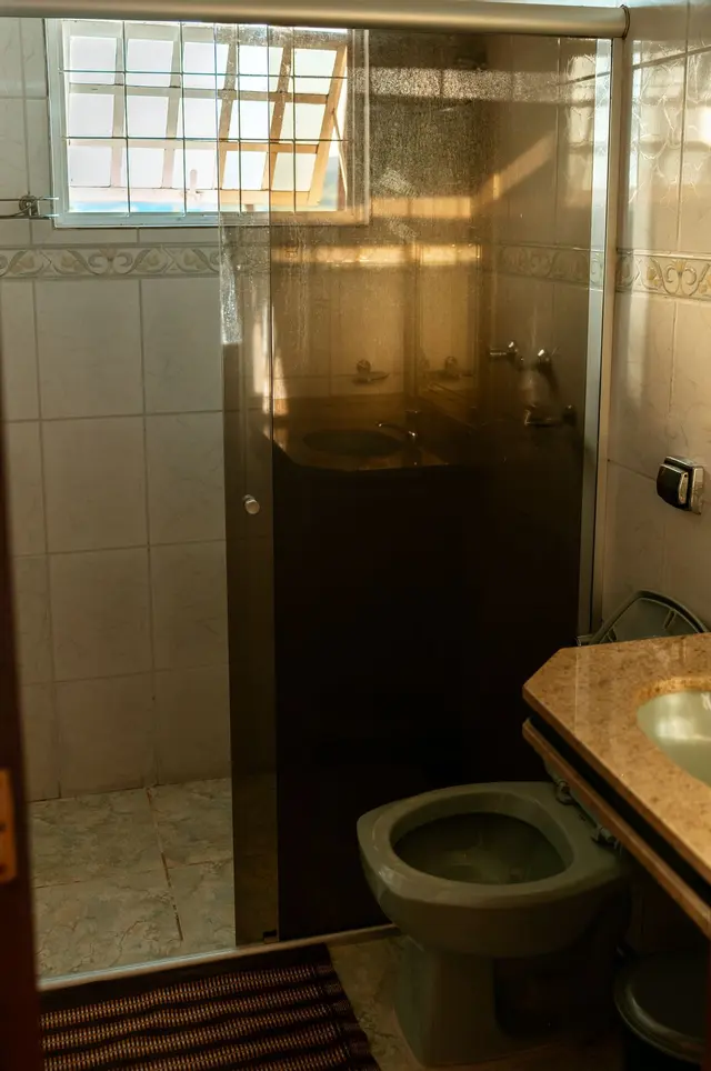 Banheiro da suíte com box de vidro e chuveiro na Pousada Solar Dona Dora