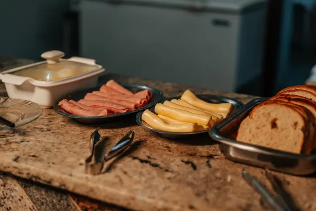 Tábua de frios com presunto, queijo e pães no café da manhã da pousada