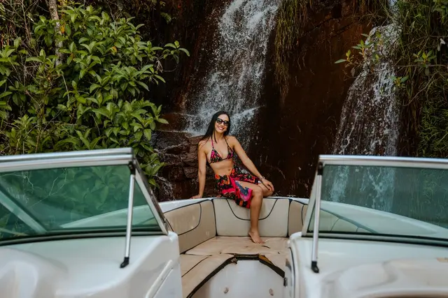 Hóspede na proa da lancha em frente a cachoeira durante passeio em Capitólio