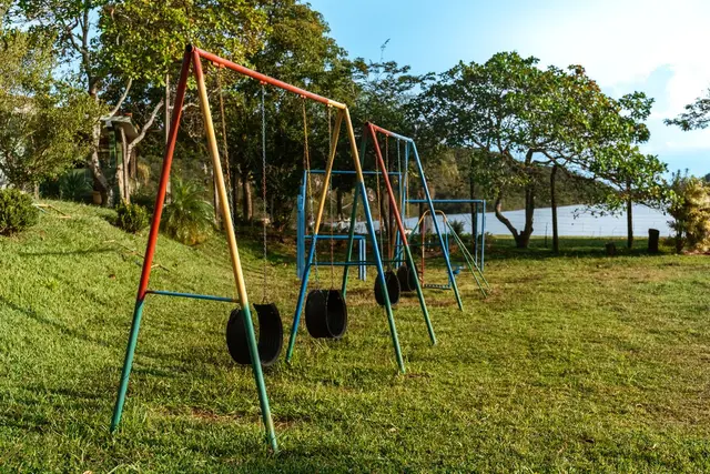 Balanços coloridos de pneu no parquinho gramado com vista do lago ao fundo