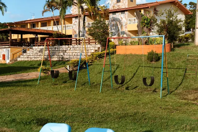 Parquinho infantil com balanços coloridos no gramado da Pousada Solar Dona Dora