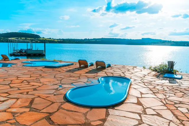 Piscinas às margens do Lago de Furnas com deck de pedra e píer ao entardecer em Capitólio