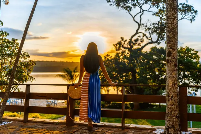 Hóspede contempla o pôr do sol sobre o Lago de Furnas do deck da Pousada Solar Dona Dora