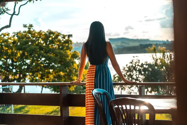 Hóspede na sacada da suíte apreciando a vista do Lago de Furnas ao entardecer em Capitólio