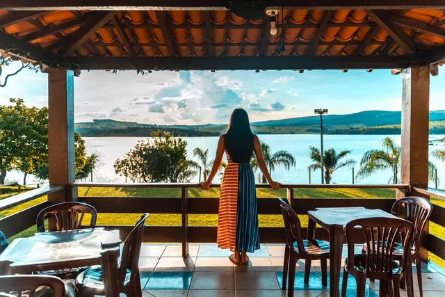 Hóspede na varanda do restaurante contemplando o pôr do sol sobre o Lago de Furnas em Capitólio