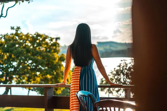 Hóspede na varanda com vista para o Lago de Furnas ao pôr do sol na Pousada Solar Dona Dora